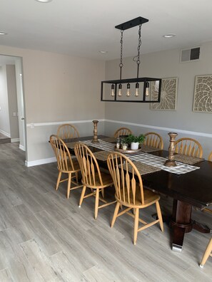 A dining area with a black table, wooden chairs, a chandelier, and decorative wall art.