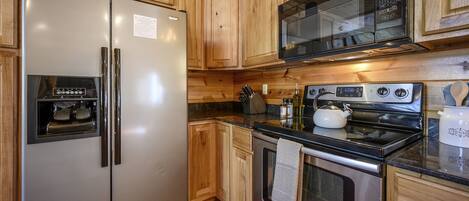 Una cocina con armarios de madera, electrodomésticos de acero inoxidable y encimera de granito.