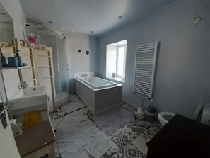 Een bad/douchecombinatie, een haardroger, handdoeken, toiletpapier