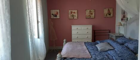 A bedroom with a bed, dresser, and a hanging light fixture.