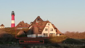 A coastal house with a lighthouse in the background.