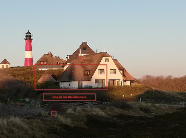 A coastal house with a lighthouse in the background.