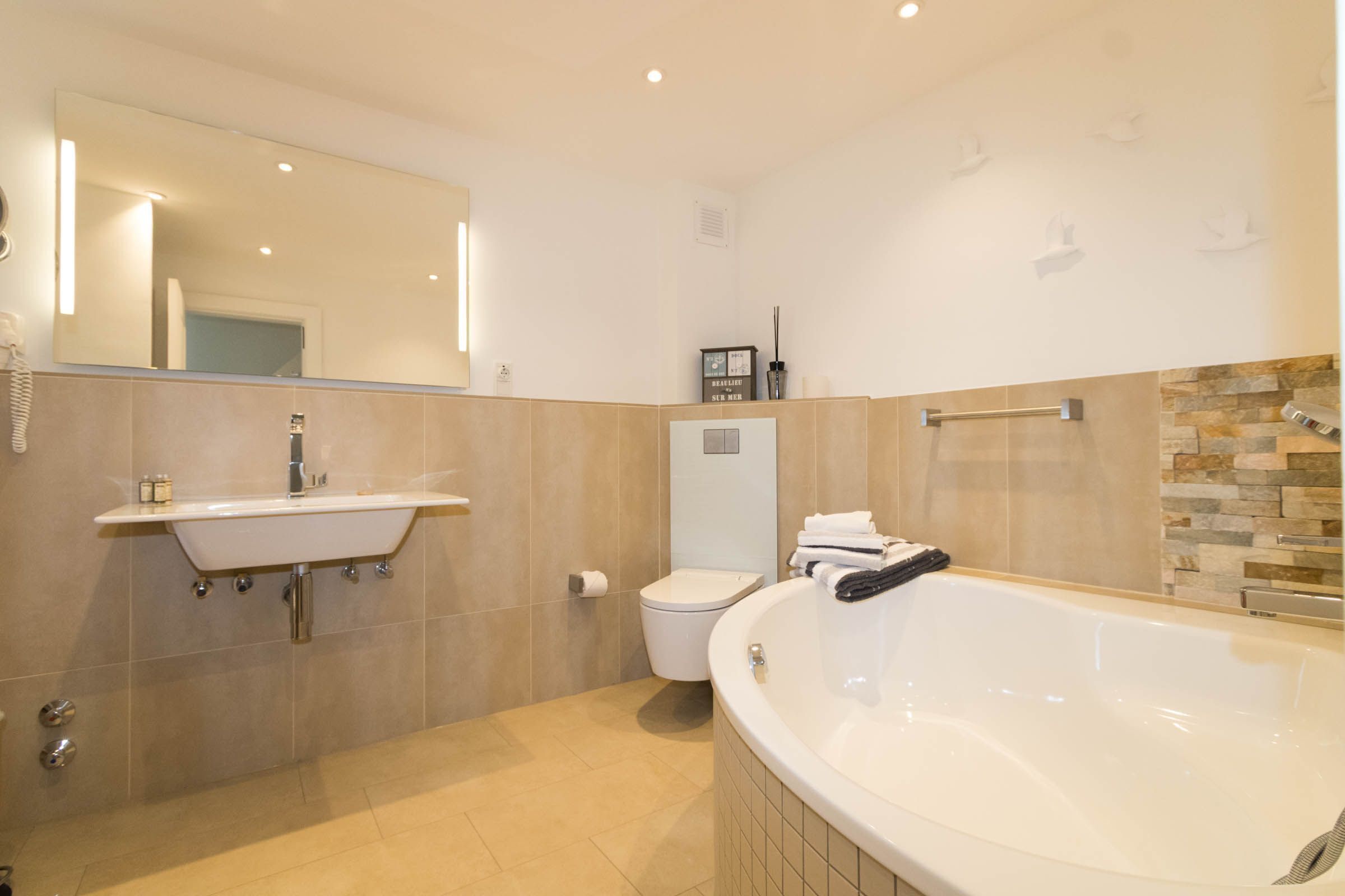 A modern bathroom with a large bathtub, a sink, and a toilet.