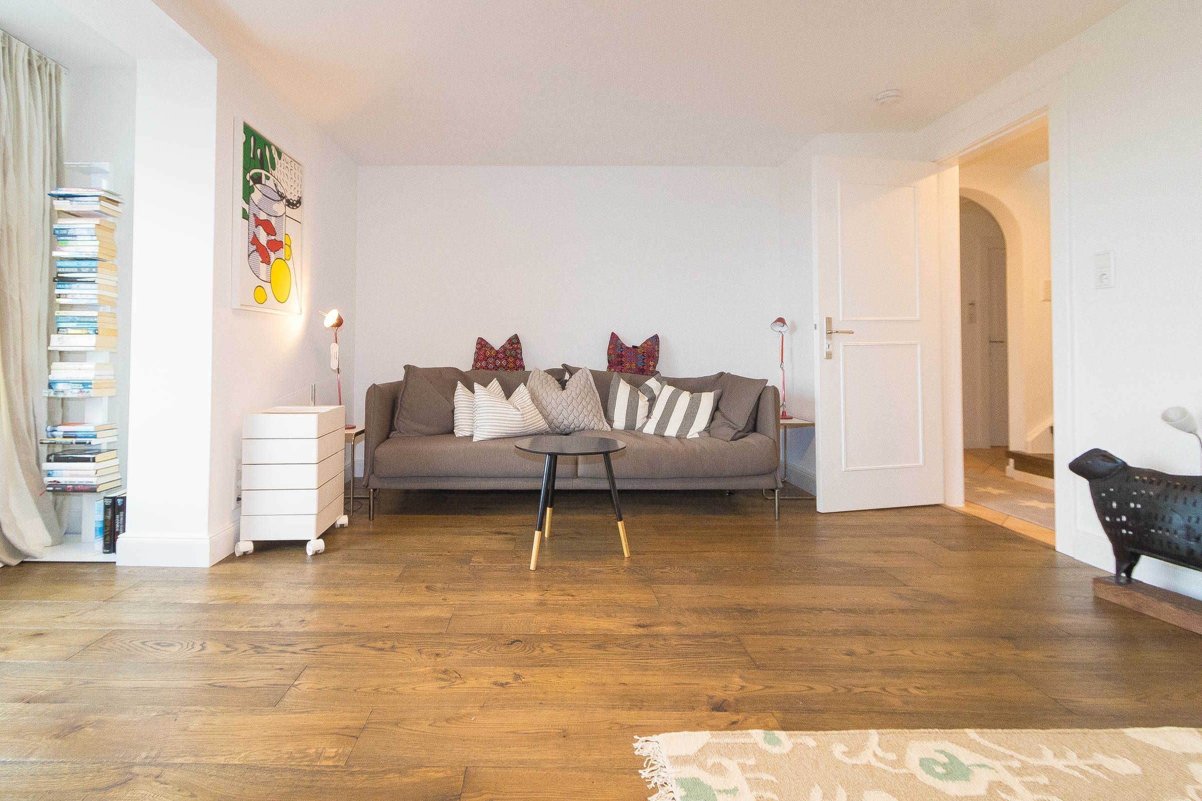 A living room with a sofa, a small side table, a bookshelf, and a bench.