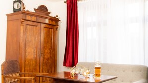 A room with a wooden table, a wooden chair, a sofa, a wooden cabinet, and a red curtain. - Historical ambience in the old Fürstenbahnhof Lübstorf (Lübstorf)