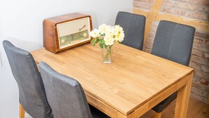 A wooden dining table with four chairs, a vintage radio, and a vase with flowers. - Historical ambience in the old Fürstenbahnhof Lübstorf (Lübstorf)