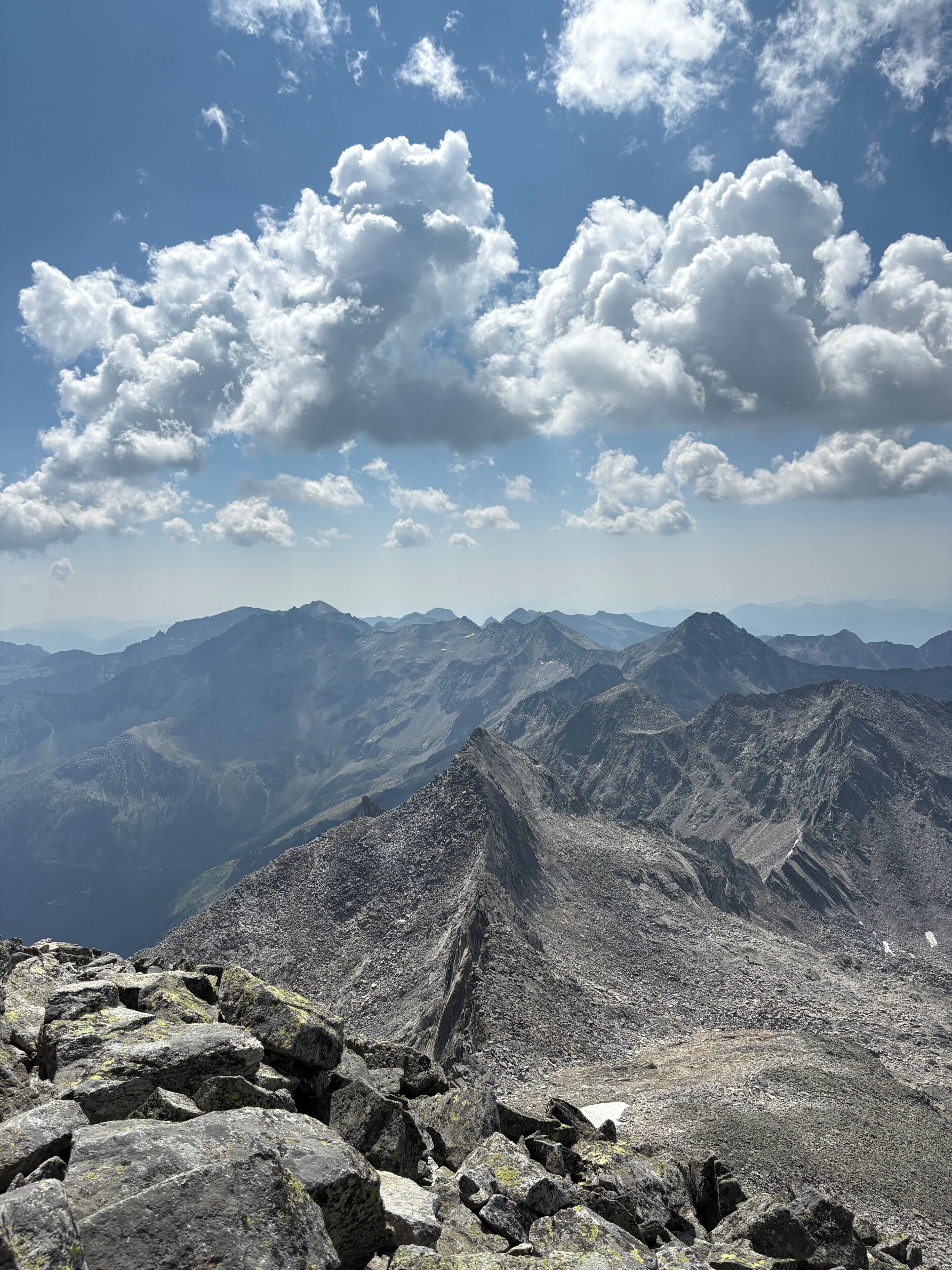 A mountainous landscape with rocky terrain and distant peaks under a partly cloudy sky.