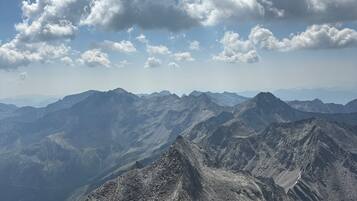 A mountainous landscape with rocky terrain and distant peaks under a partly cloudy sky.