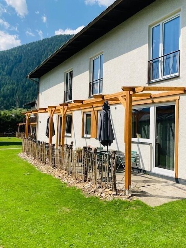 Un edificio con múltiples ventanas y una estructura de pérgola de madera.