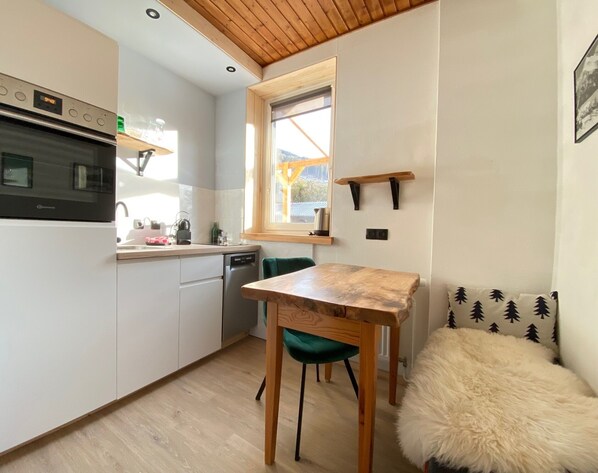 Une cuisine compacte dotée d’un four encastré, d’une fenêtre et d’un coin repas avec une table et des chaises.