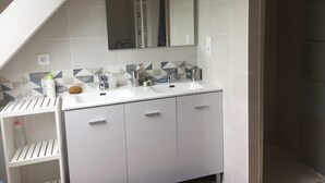 Un baño moderno con tocador blanco, un espejo grande y un salpicadero de azulejos geométricos.