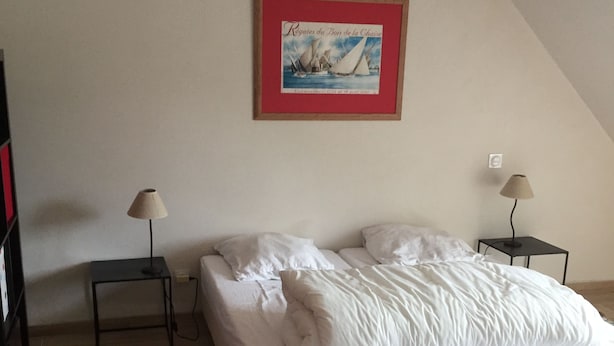 Un dormitorio con una cama, dos mesitas de noche, una lámpara en cada una, un cuadro en la pared y una alfombra en el suelo.