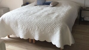 Un dormitorio con una cama grande, una araña y una mesita de noche con lámpara.