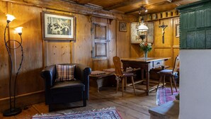 Une pièce chaleureuse avec des murs en bois, un canapé en cuir noir, une table à manger en bois et une chaise en bois.