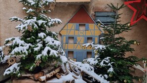 Un espace extérieur enneigé avec une maquette de maison et un sapin de Noël.