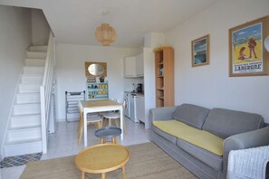 A compact living space with a staircase, a dining area, a kitchen, and a seating area with a sofa and a small table.