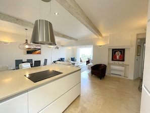 A modern kitchen with a central island, pendant lighting, and a dining area with a view.