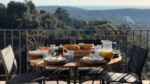 Ein Tisch gedeckt mit Tellern, Gläsern und einem Brotkorb, mit Blick auf eine malerische Landschaft.