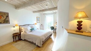 Ein Schlafzimmer mit Bett, Nachttischen, einer Lampe und Blick ins Freie.