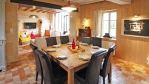 Un comedor con una mesa de madera dispuesta para cuatro personas, rodeada de sillas, con un ventanal grande y paredes de madera.