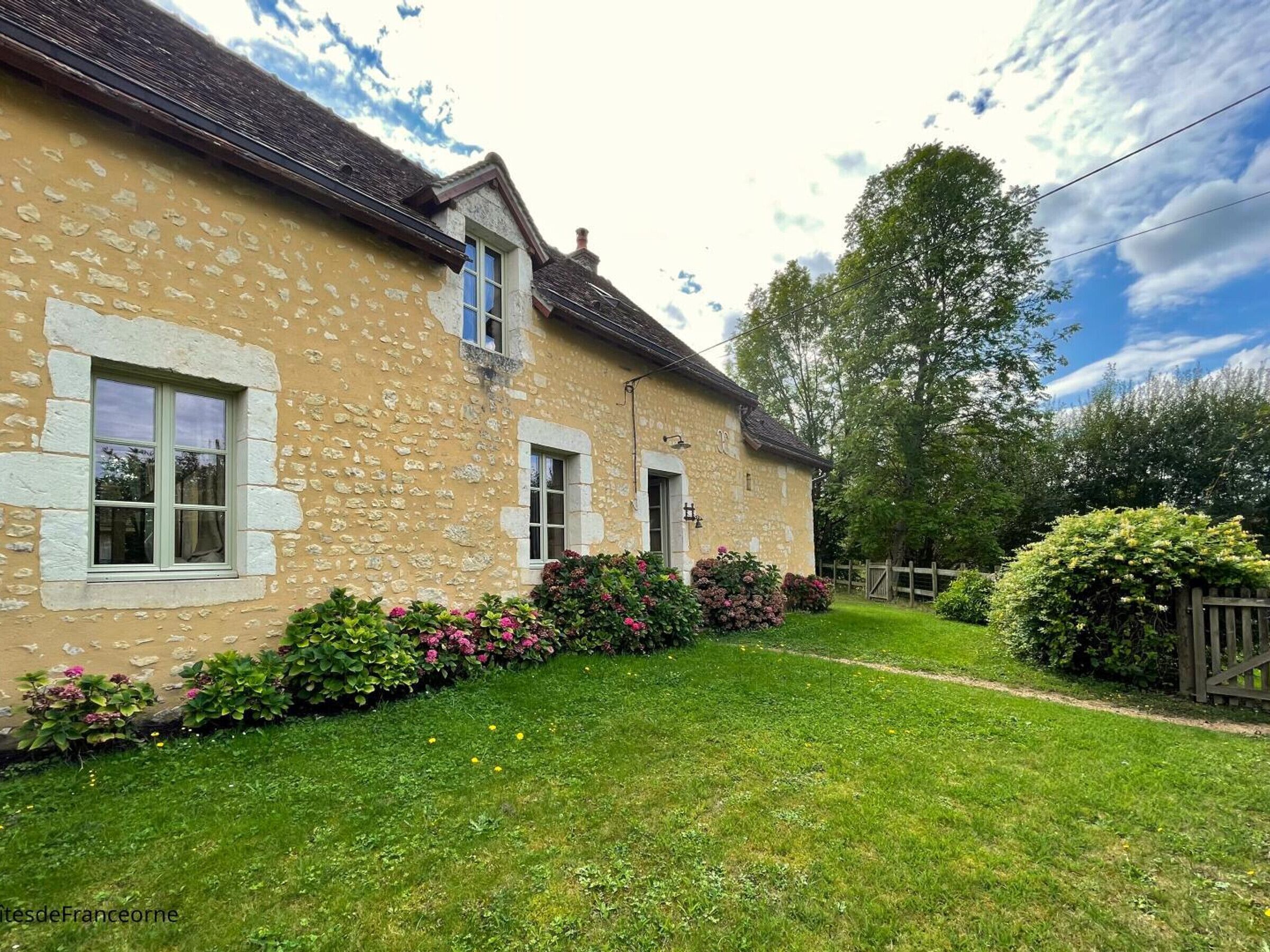 A stone house with a well-maintained garden and a wooden fence.