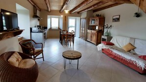 A spacious living area with a dining table, sofa, and kitchen in the background. - Renovated cottage in the heart of Auvergne (Arlempdes)