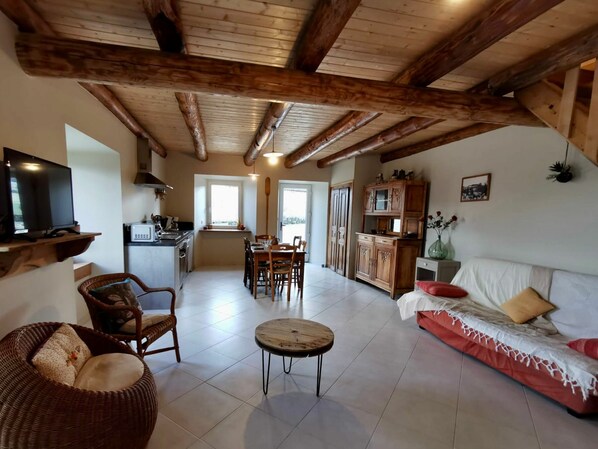 A spacious living area with a dining table, sofa, and kitchen in the background.