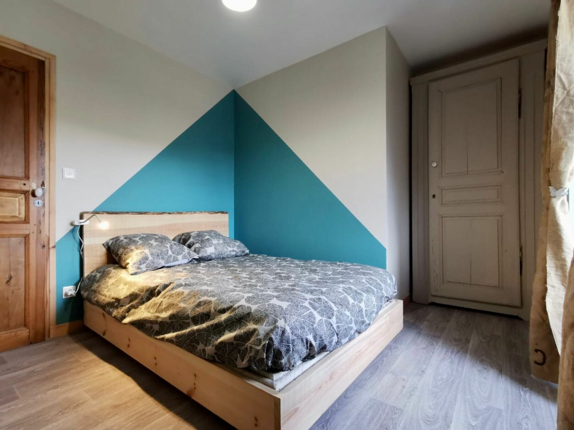 A bedroom with a bed, wooden headboard, and a blue accent wall.
