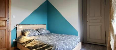 A bedroom with a bed, wooden headboard, and a blue accent wall.