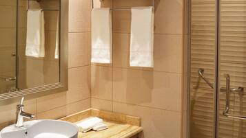 A modern bathroom with a round sink, a large mirror, and a glass shower enclosure.