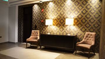 A lobby with two armchairs, a console table, and patterned wallpaper.