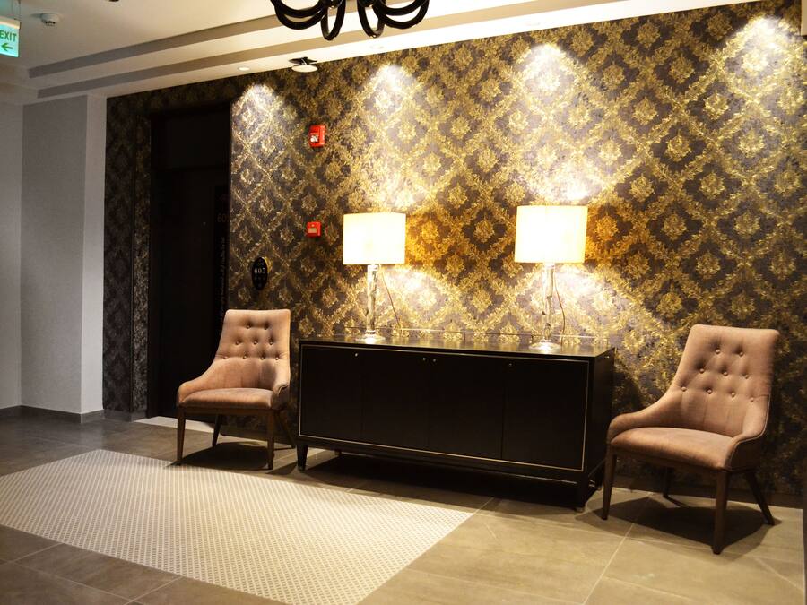 A lobby with two armchairs, a console table, and patterned wallpaper.