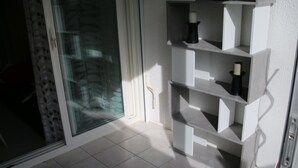 A modern room with a glass door, white tiled floor, and built-in shelving with decorative items.