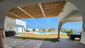 An outdoor patio area with a pool, a covered seating area, and a view of the surrounding landscape. - Very large villa ideal for groups of up to 15 to 18 people (Kélibia)