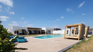 A pool area with a wooden deck, a pool, and a covered seating area. - Very large villa ideal for groups of up to 15 to 18 people (Kélibia)