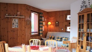 A cozy room with wooden walls, a dining table set with plates and glasses, a sofa, and a cabinet with dishes. - Cozy 2-Bed Apartment with Balcony, 100m from Slopes and Shops in Vars Les Claux (Vars)