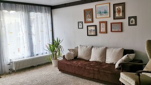 A living room with a brown sofa, a chair, and a radiator. There are several framed pictures on the wall. - Cozy terraced vacation home with wood-burning fireplace (Bernau im Schwarzwald)