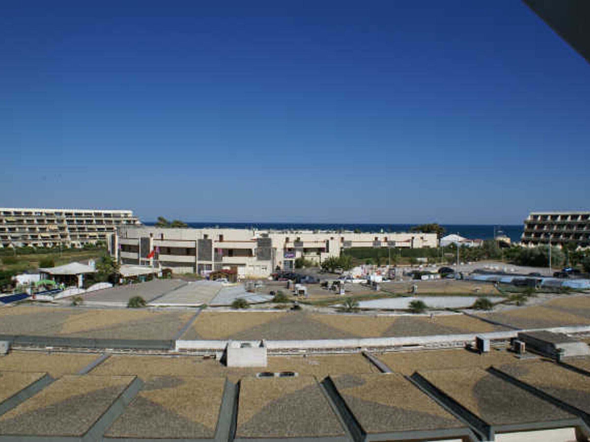 Un hôtel situé sur la côte, avec plusieurs étages, un parking et une vue sur la mer.