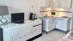 Une petite cuisine équipée d’un four à micro-ondes, d’une bouilloire et d’une machine à café.