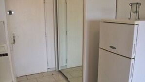 Une pièce avec une porte blanche, un réfrigérateur blanc et un sol carrelé.