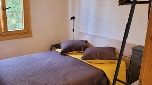 A single bed with a wooden frame, a bedside table, a lamp, and a window with a view of greenery. - Porticcio house near the sea (Grosseto-Prugna)