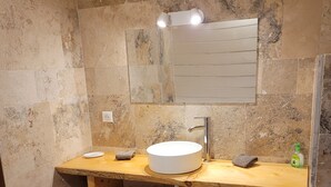 A bathroom with a stone wall, a wooden vanity with a sink, a mirror, and a towel rack. - Porticcio house near the sea (Grosseto-Prugna)
