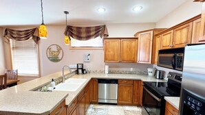 Una cocina moderna con armarios de madera, un refrigerador de acero inoxidable, un microondas y un lavavajillas.