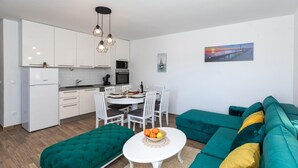 Un espace de vie compact comprenant un coin cuisine, un coin repas et un ensemble de canapés.