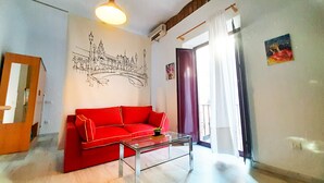 A living room with a red sofa, a glass coffee table, and a wall mural of a bridge. - 2 balconies! Lovely Center Apartments Alfalfa (Sevilla)