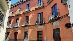 A multi-story building with balconies, a red door, and a small shop on the ground floor. - 2 balconies! Lovely Center Apartments Alfalfa (Sevilla)