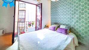 A bedroom with a bed, a balcony, and patterned wallpaper. - 2 balconies! Lovely Center Apartments Alfalfa (Sevilla)