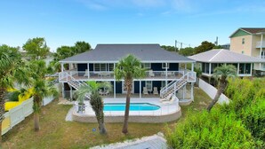 A two-story house with a pool, surrounded by palm trees and a white fence. - Blue Lagoon - Lakefront Getaway Private Pool, One Block to the Beach, Sleeps 12 (Panama City Beach)