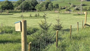 A rural landscape with a wooden fence, a small wooden structure, and a clear view of the countryside. - Cosy Annexe Sleeps 4 (Holyhead)