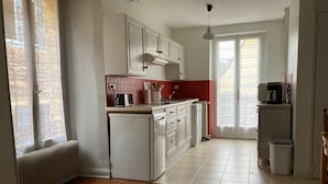 A kitchen with white cabinets, a red backsplash, a built-in oven, a coffee maker, and a window with a view.